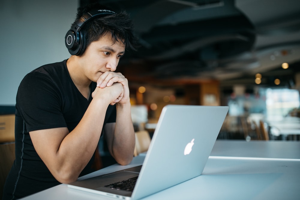 坐在 MacBook 前的椅子上戴着耳机的男人