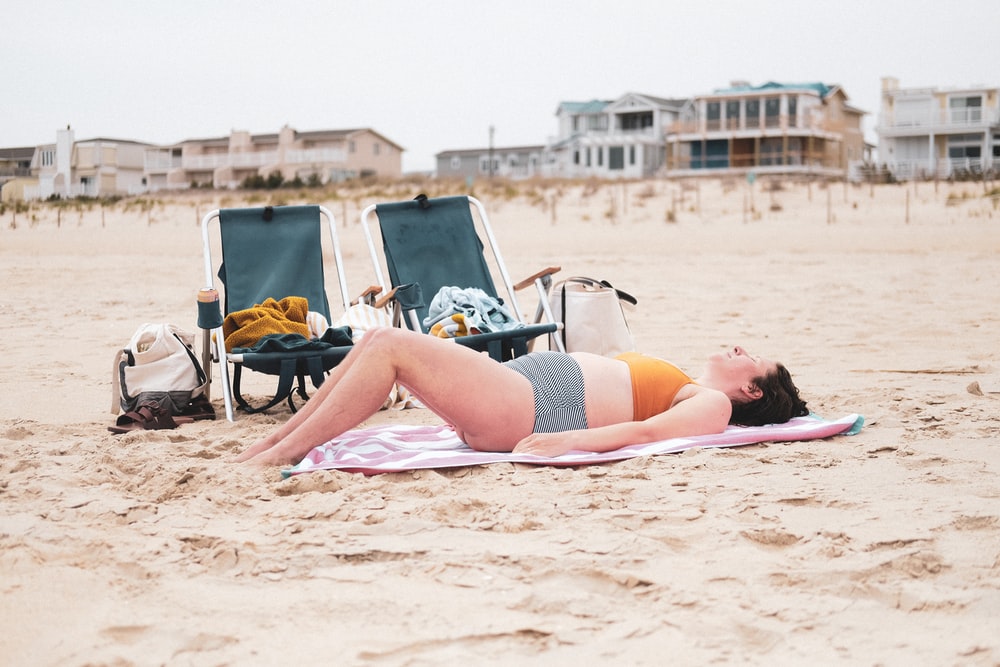 白天躺在沙滩上的黑色比基尼的女人