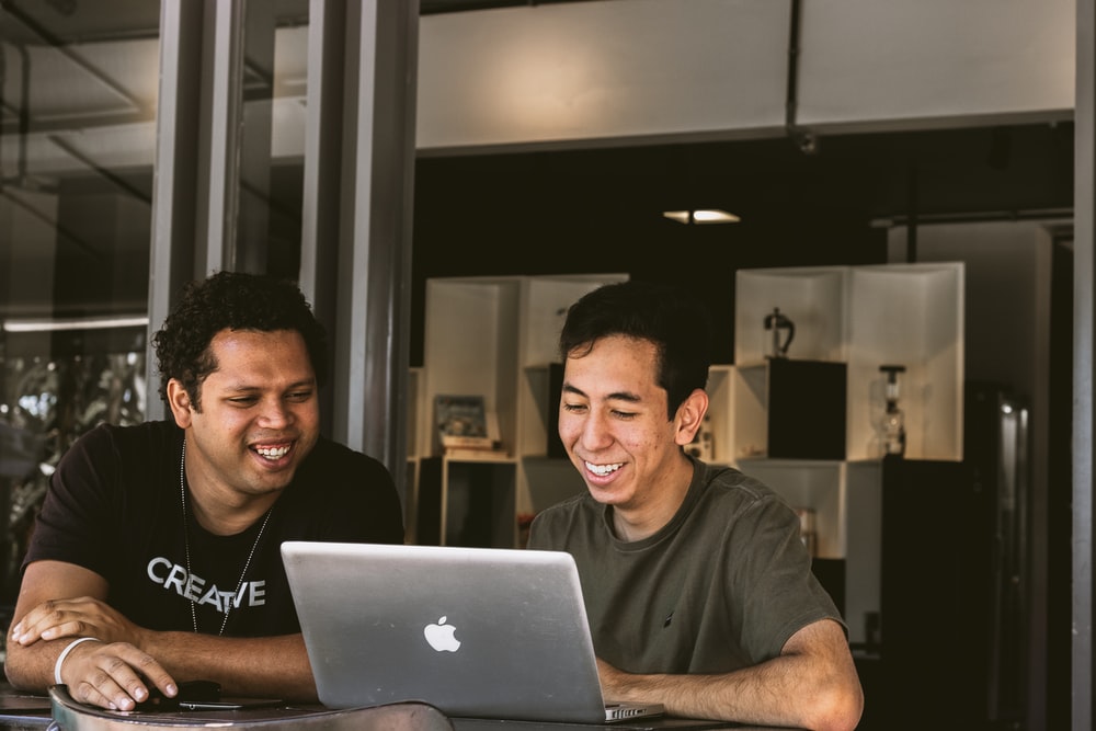 两个微笑的男人看着 MacBook
