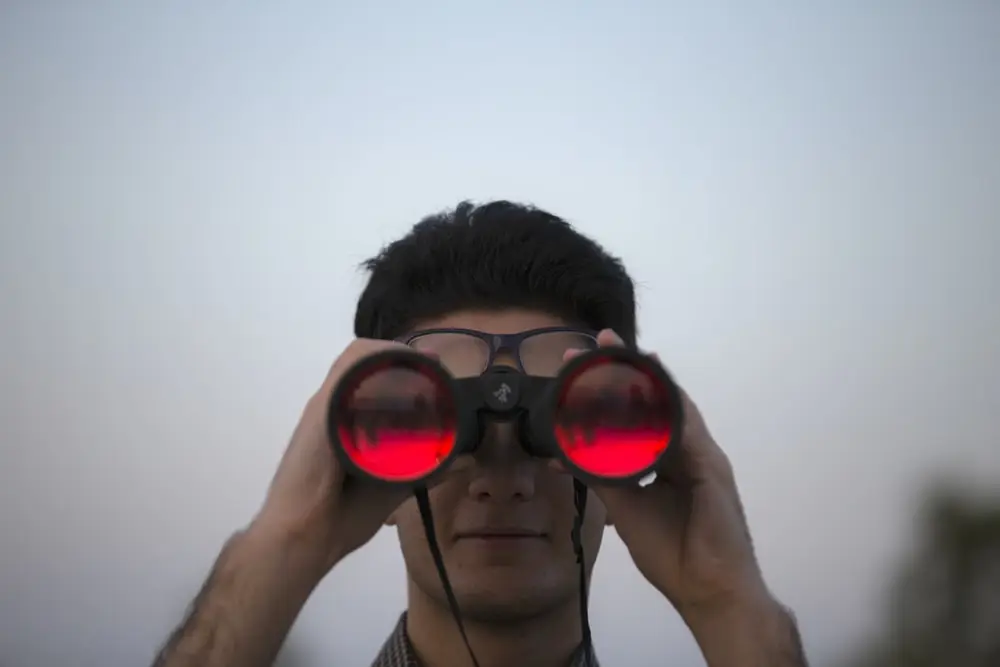 拿着黑色双筒望远镜的人