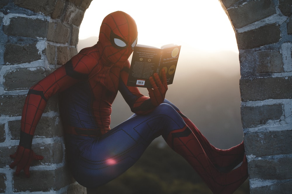 蜘蛛侠靠在水泥砖上看书