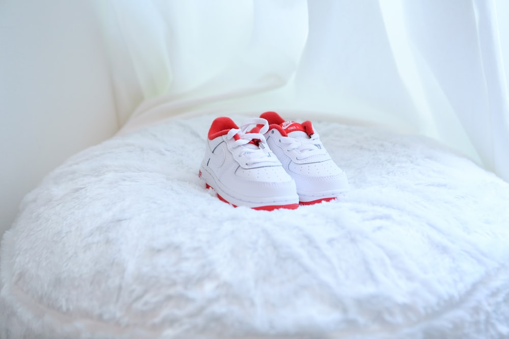 white and red nike sneakers on white textile