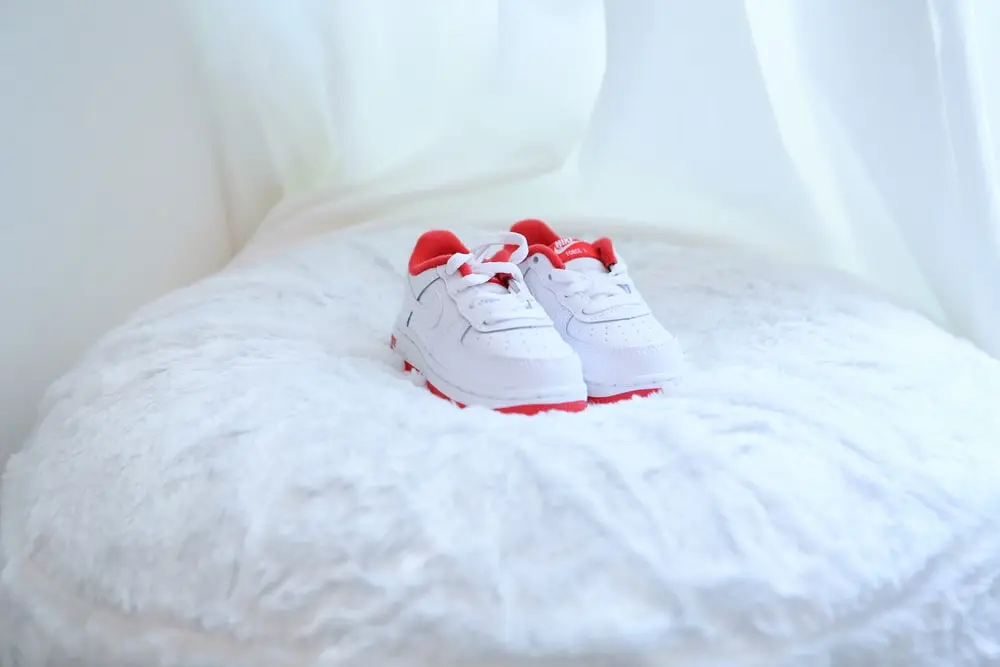 white and red nike sneakers on white textile