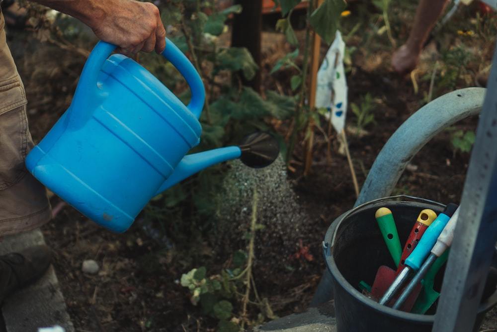 blue plastic watering can on black plastic bucket