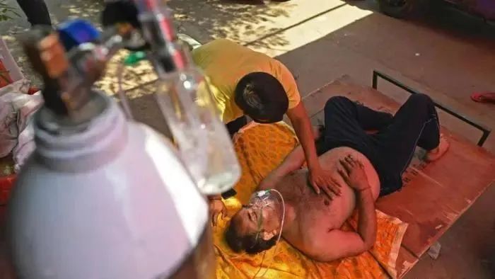 当地时间4月26日,印度加兹阿巴德,一名新冠患者在路边搭建的帐篷内吸氧。近日,印度新冠患者确诊病例连续出现增长高峰,几天内新增病例超百万,印度多地医院出现床位短缺、氧气供应困难等现象,许多病人只能在户外等候接受治疗。